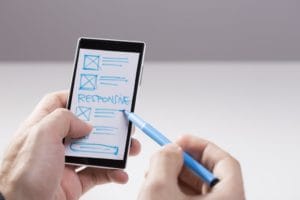 hand holding phone with blue web design and pen