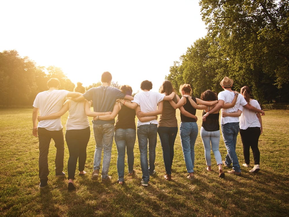 Group of people in a park linking arms - We all need a tribe to belong to