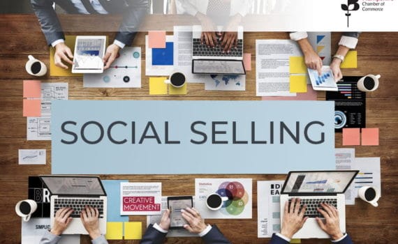 Social selling written on a backdrop of a wooden table with people around it