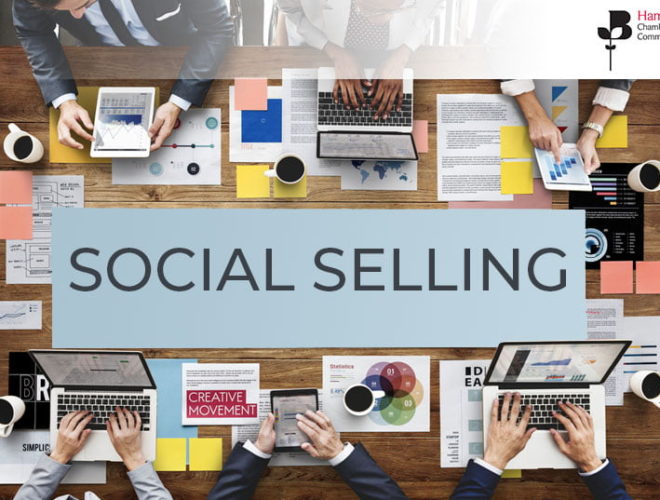 Social selling written on a backdrop of a wooden table with people around it