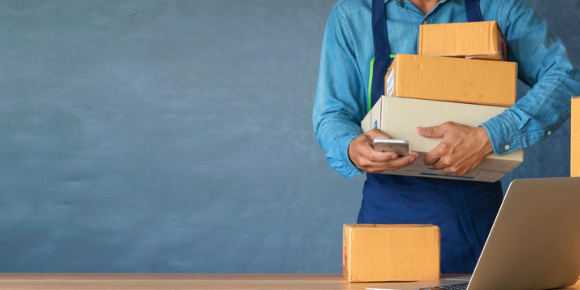 A man in a blue shirt holds cardboard boxes