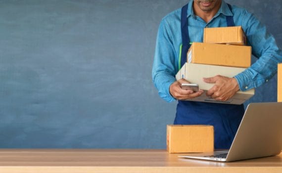 A man in a blue shirt holds cardboard boxes