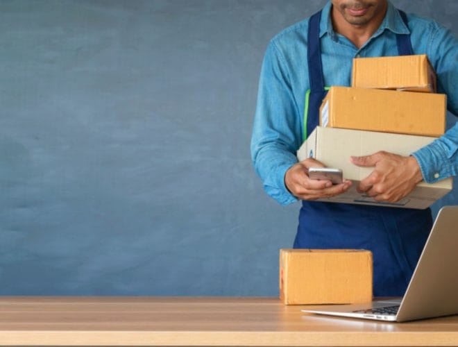 A man in a blue shirt holds cardboard boxes