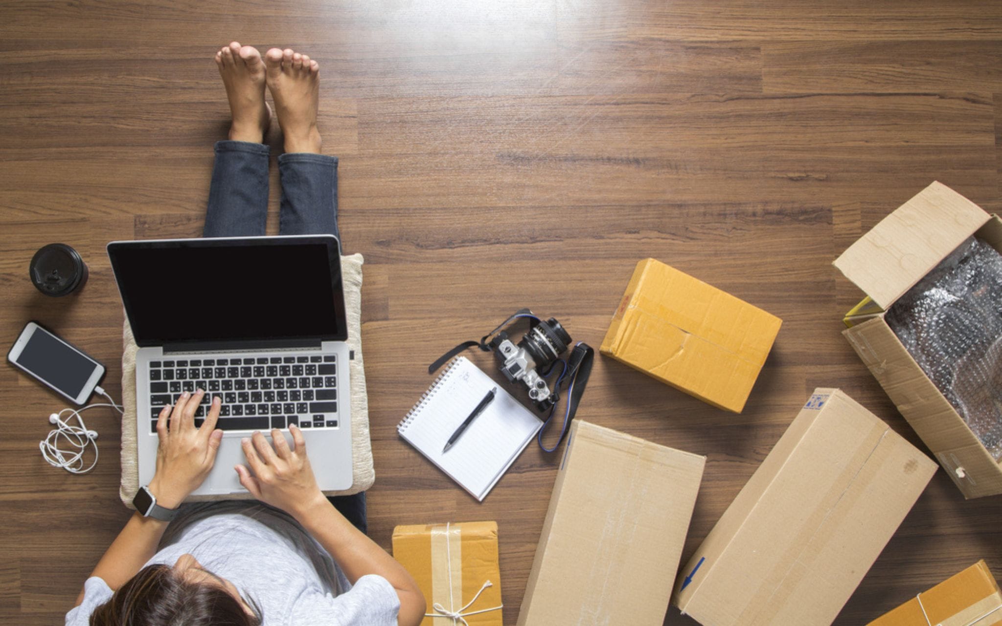 Aerial view of a woman working on her laptop beside cardboard boxes