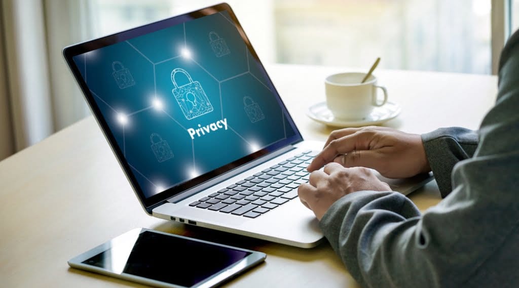 Someone's hands using a laptop displaying the word privacy and a padlock