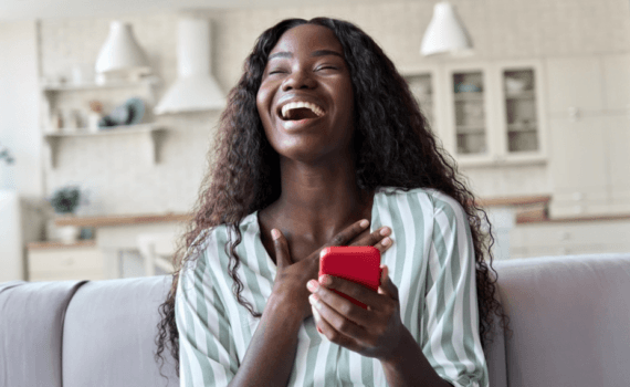 A young woman laughs after looking at her phone
