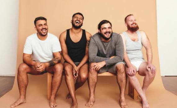 A diverse range of men sitting on a bench laughing