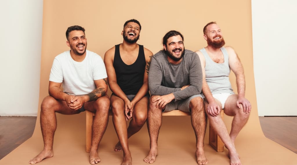 A diverse range of men sitting on a bench laughing