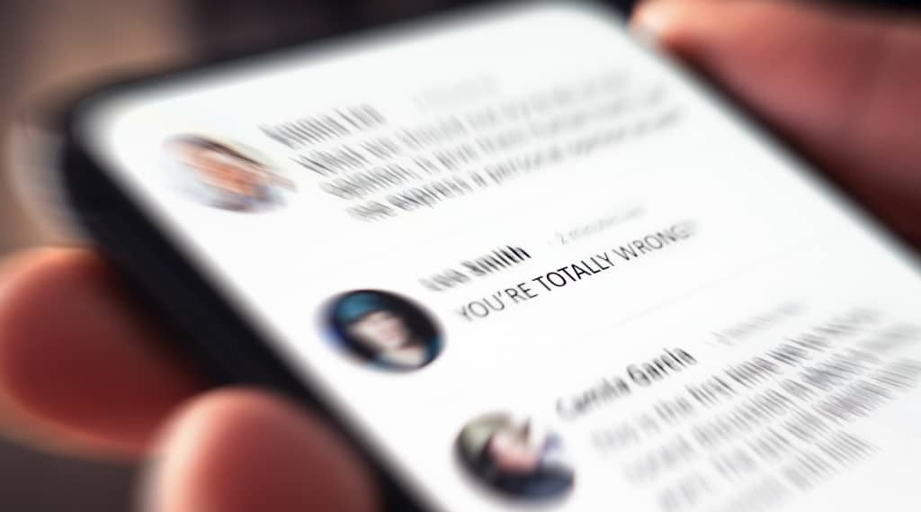 A smartphone screen displaying a heated social media comment reading “YOU’RE TOTALLY WRONG,” suggesting online conflict or digital backlash.