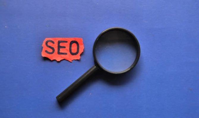 Magnifying glass beside red paper reading “SEO,” symbolising SEO agency and SEO packages.