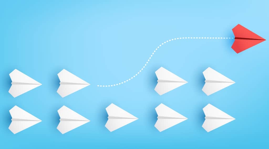 Illustration of red paper plane changing direction from white paper planes