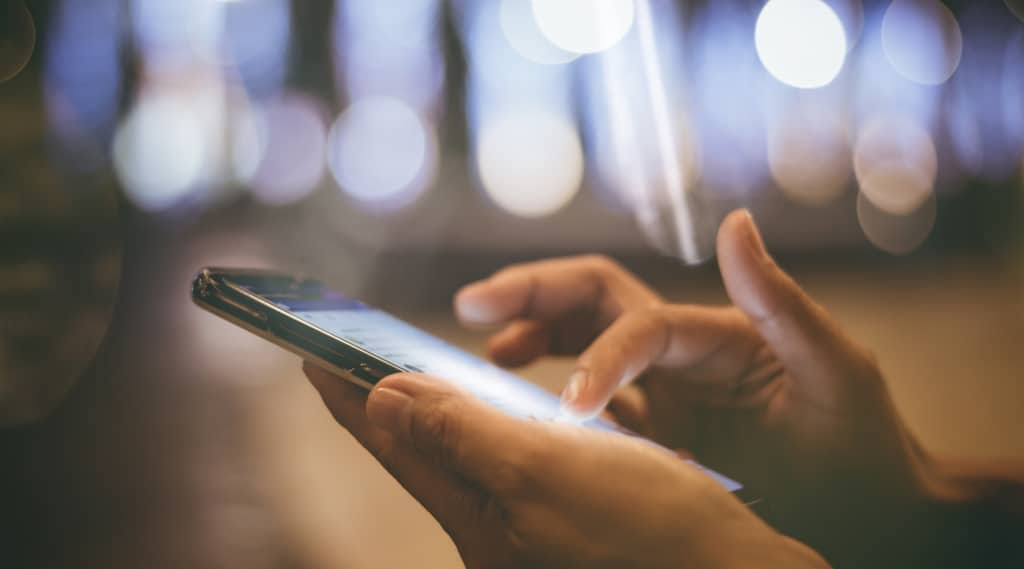 Hands using smartphone at night, representing mobile web design and site speed’s impact on conversion rates.