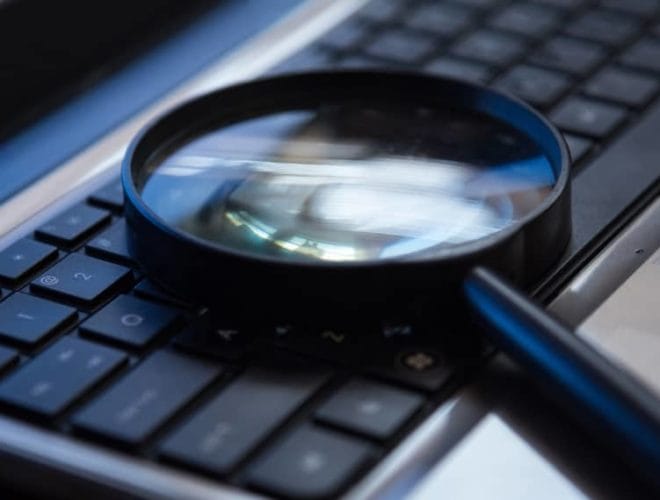 Magnifying glass placed on a laptop keyboard for search or analysis concept
