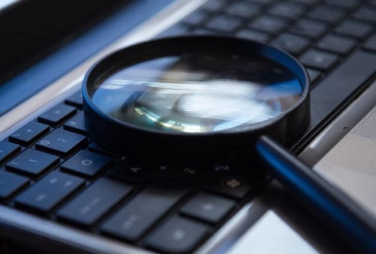 Magnifying glass placed on a laptop keyboard for search or analysis concept