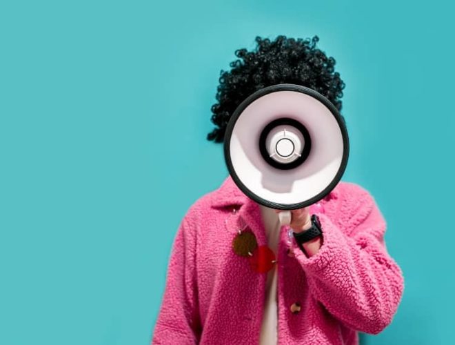 Person in a bright jacket shouting through a megaphone, representing digital marketing, advertising and seasonal business strategy.