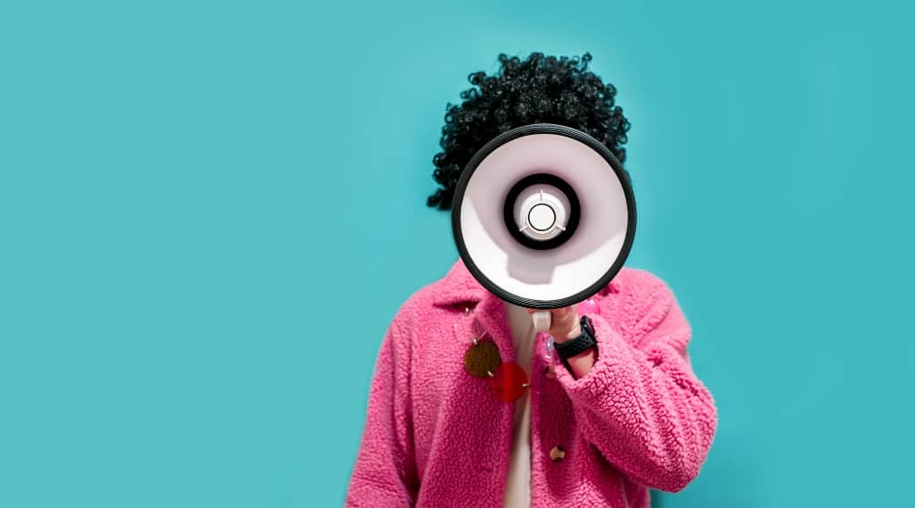 Person in a bright jacket shouting through a megaphone, representing digital marketing, advertising and seasonal business strategy.