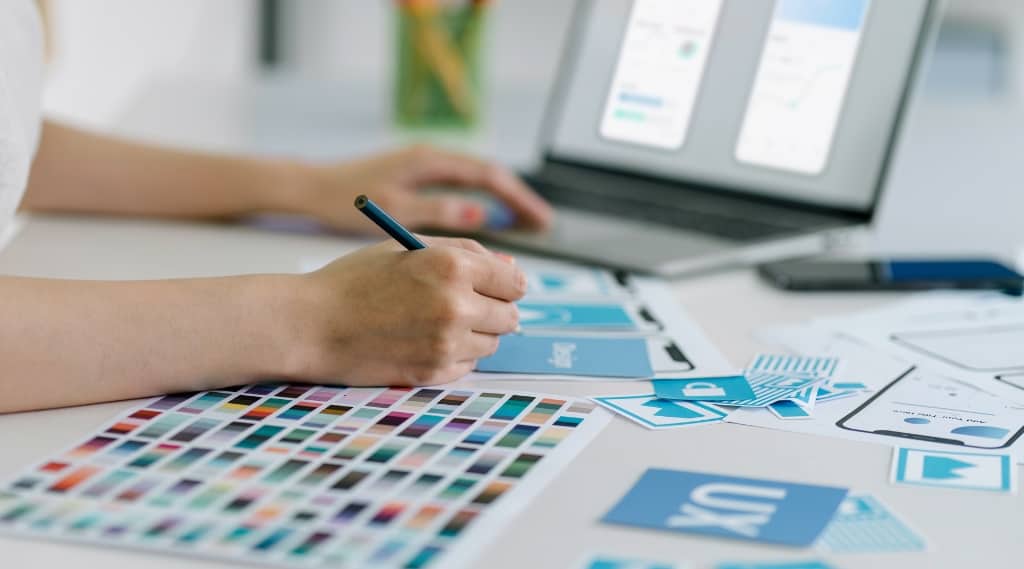 Designer working on web design and web development with colour palettes and UX layouts, showing marketing agency creativity beyond ChatGPT prompts.