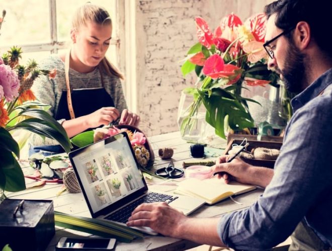 small business web design florist, a florist workshop where two people work with flowers beside an open laptop showing an online shop