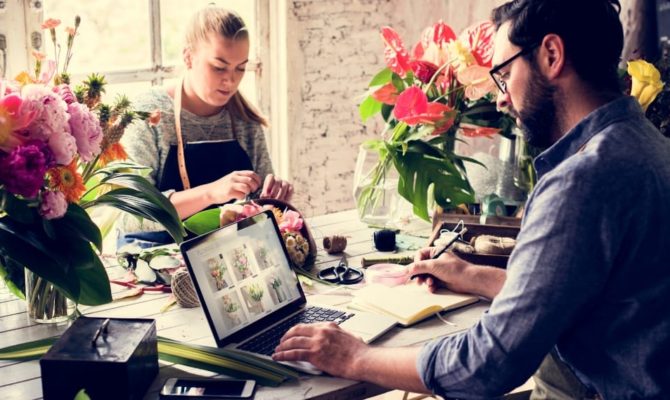 small business web design florist, a florist workshop where two people work with flowers beside an open laptop showing an online shop