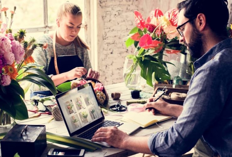 small business web design florist, a florist workshop where two people work with flowers beside an open laptop showing an online shop