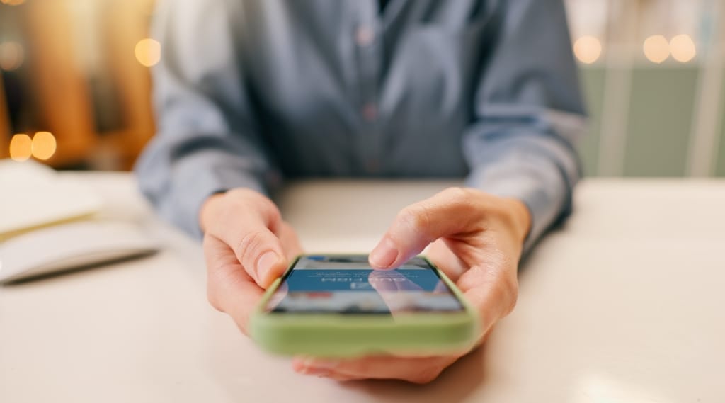 small business web design for mobile optimisation, a person using a smartphone at a desk with soft lighting in the background