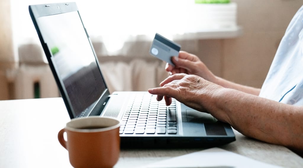 Marketing funnel explained: Person shopping online with a credit card and laptop, representing conversion and the final stage of a marketing funnel.