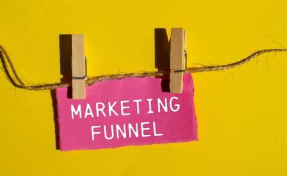 What is the marketing funnel: Marketing funnel sign clipped to a string against a yellow background, illustrating what a marketing funnel is and how it works.