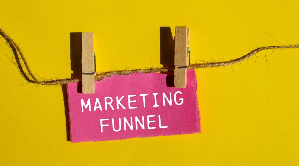 What is the marketing funnel: Marketing funnel sign clipped to a string against a yellow background, illustrating what a marketing funnel is and how it works.