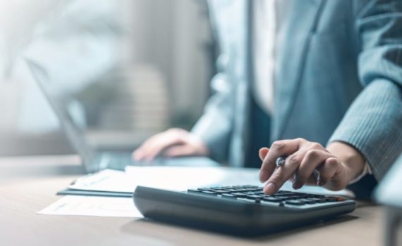 Should you cut your marketing spend: business professional using a calculator at a desk reviewing documents.