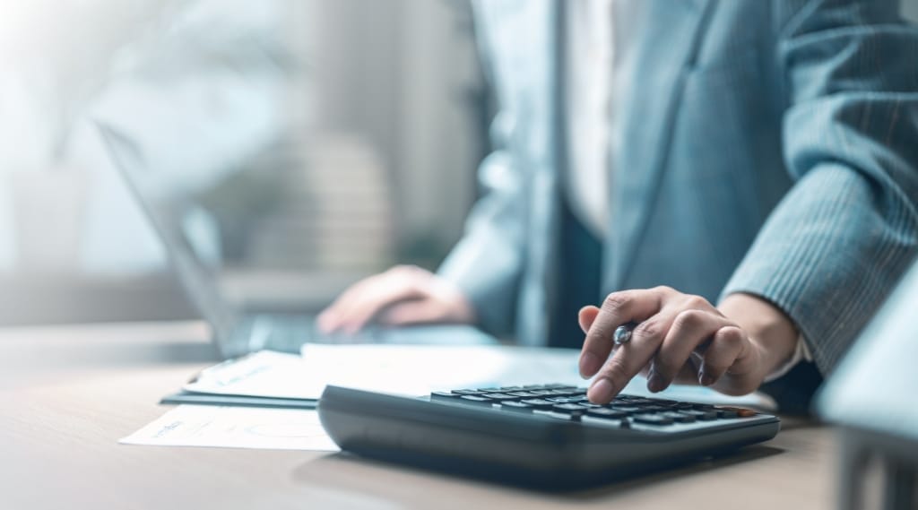 Should you cut your marketing spend: business professional using a calculator at a desk reviewing documents.