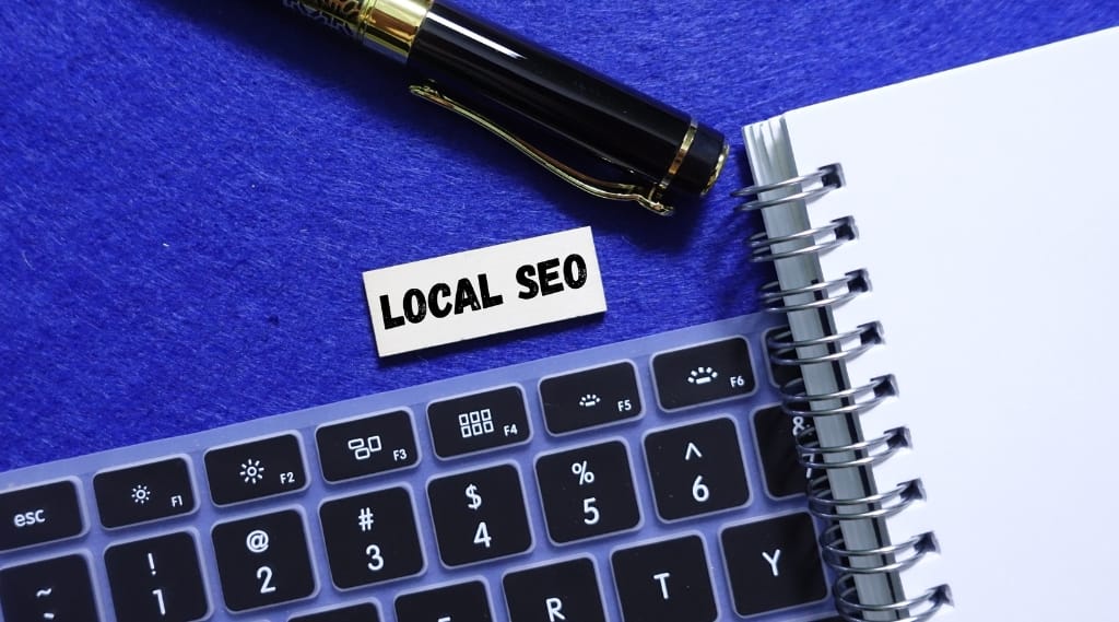 Keyboard and notebook with “Local SEO” label beside pen, representing local SEO strategies for improving search rankings.
