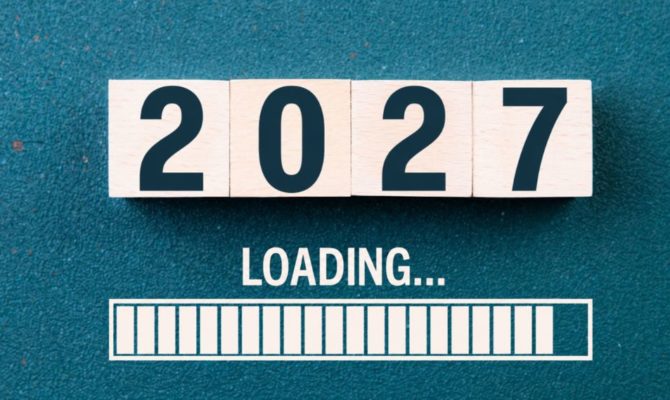 how much should I spend on marketing in 2027: Four wooden blocks spelling “2027” on a teal surface, above the word "Loading..." and a nearly full white loading bar.