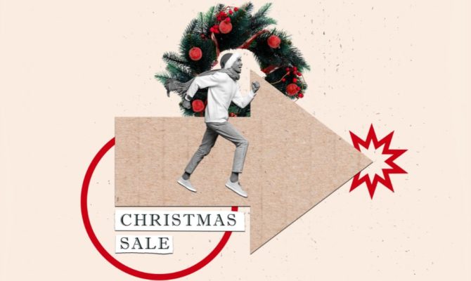 when do Christmas shoppers start researching: A collage of a smiling man in a bobble hat, scarf and jumper running along a large cardboard arrow, in front of a Christmas wreath with red baubles. Text cut-outs below read “Christmas Sale”, next to a red starburst and a red circle.